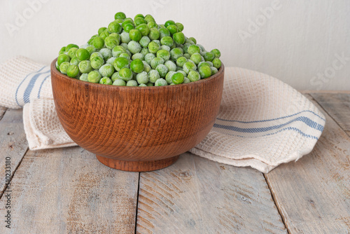 Young frozen green peas on wooden table viewed from above. Green pea pod table peas. Closeup of fresh green peas (Pisum sativum)