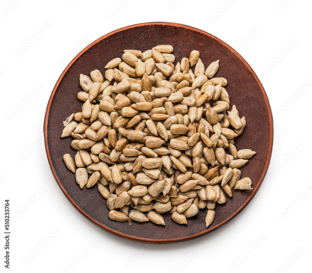 Plate with peeled sunflower seeds on white background