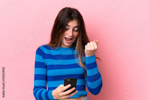 Young caucasian woman isolated on pink background surprised and sending a message