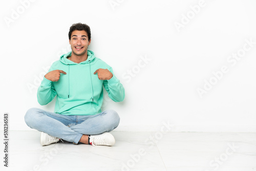 Caucasian handsome man sitting on the floor with surprise facial expression