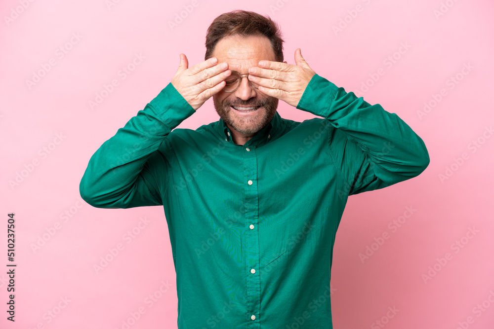Middle age caucasian man isolated on pink background covering eyes by hands and smiling Middle age caucasian man isolated on pink background covering eyes by hands and smiling