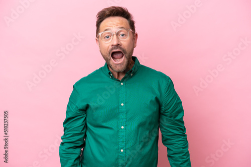 Middle age caucasian man isolated on pink background with surprise facial expression