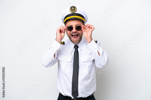 Airplane middle age pilot isolated on white background with glasses and surprised