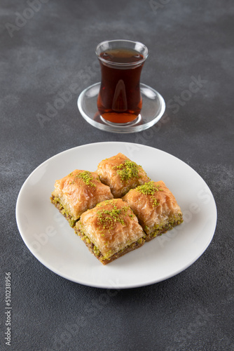 Pistachio baklava on a white plate with Turkish tea 