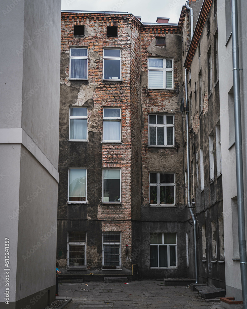 An old neglected yard with a dilapidated tenement house.