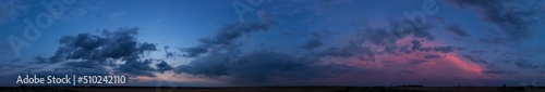 A wide majestic view of a panoramic dark sunset over the fields.