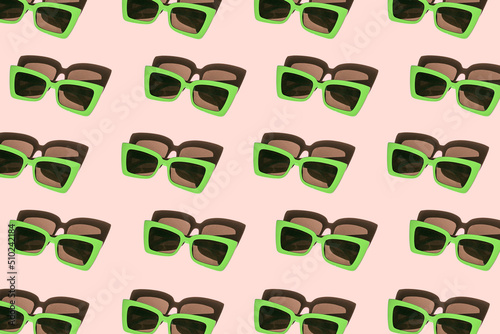 Creative pattern made of bright green sunglasses on pastel pink background. Summer fashion concept. Minimal style. Top view. Flat lay
