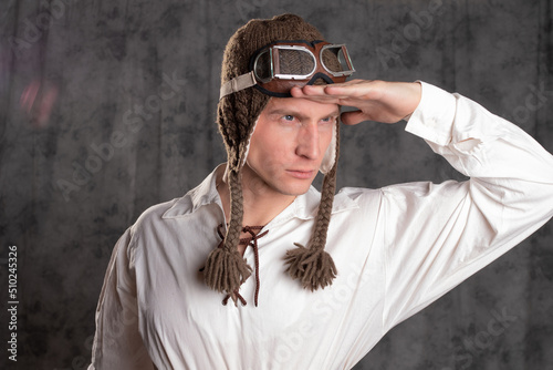 A test pilot, a dreamer. A young man in a funny knitted earflaps and flight glasses, looks into the distance, a flight hat and goggles.