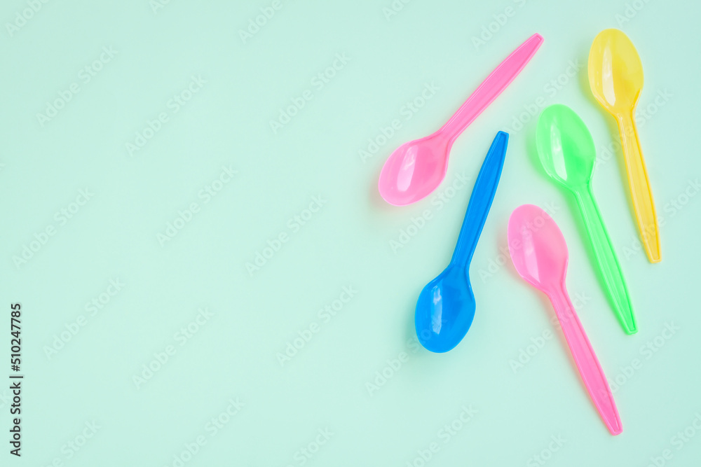 Multicolor plastic spoons on green background Multicolor plastic spoons on green background