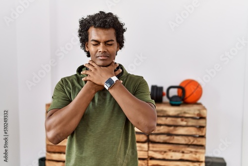 African man with curly hair wearing sportswear at the gym shouting and suffocate because painful strangle. health problem. asphyxiate and suicide concept.
