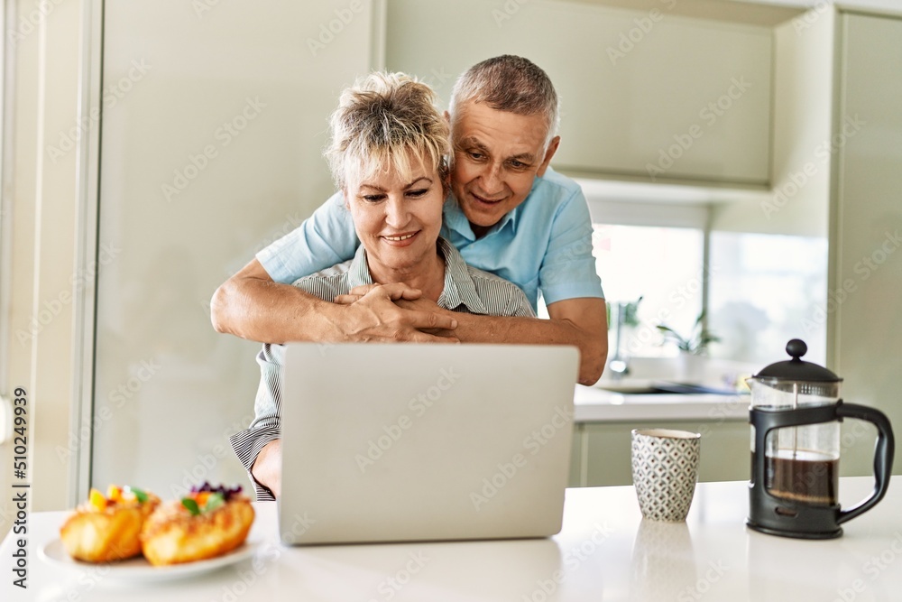 Senior caucasian couple having breakfast using laptop at the kitchen. Senior caucasian couple having breakfast using laptop at the kitchen.