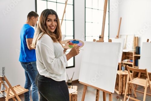 Two students smiling happy painting at art school.