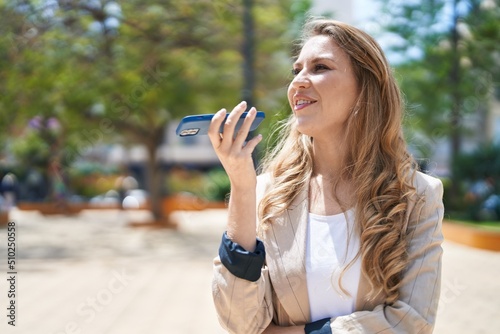 Young blonde woman smiling confident talking on the smartphone at park