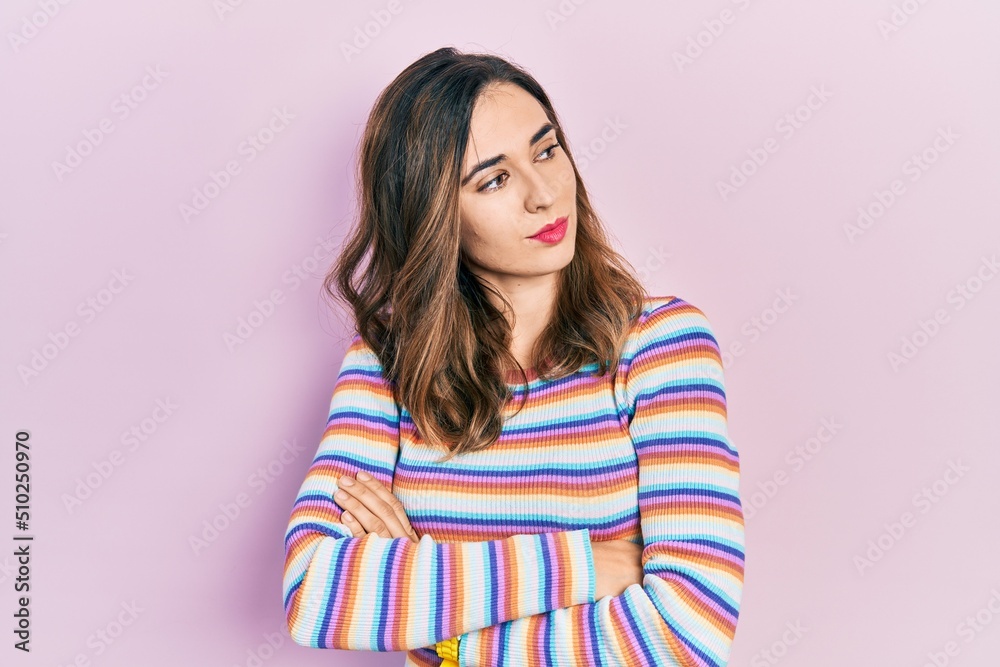 Young hispanic girl wearing casual clothes looking to the side with arms crossed convinced and confident