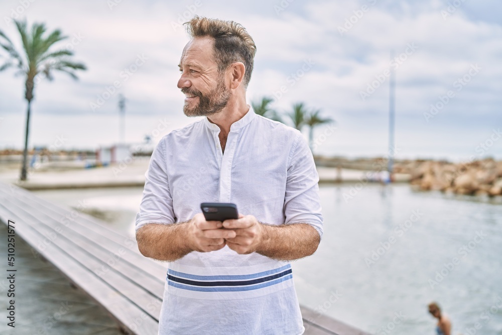 Middle age man using smartphone by the sea