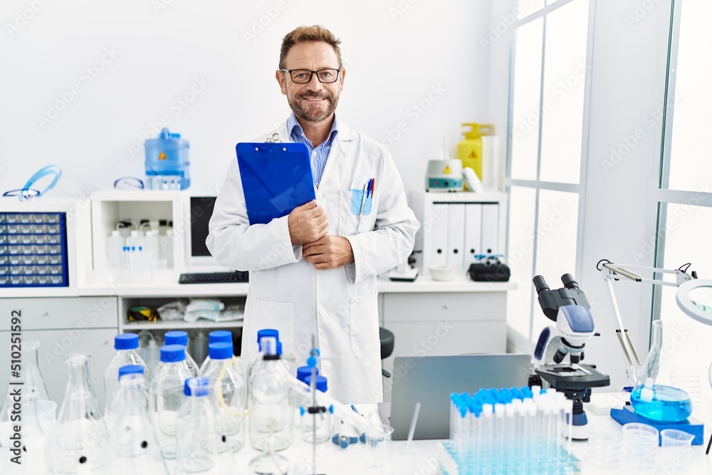 Middle age hispanic man smiling confident wearing scientist uniform at laboratory Middle age hispanic man smiling confident wearing scientist uniform at laboratory