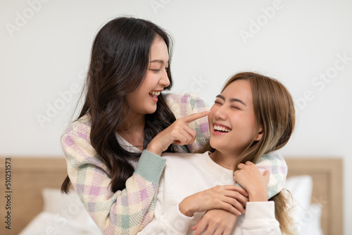Beautiful two female LGBT lesbian embracing and looking together with love and romance on bed.Positive mood and moment of LGBTQ lesbian lying on white bed relax and comfort.LGBTQ Lifestyle Concept