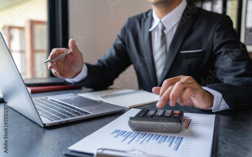 Asian male accountant or banker making calculations. Savings, finances and economy concept through a laptop.