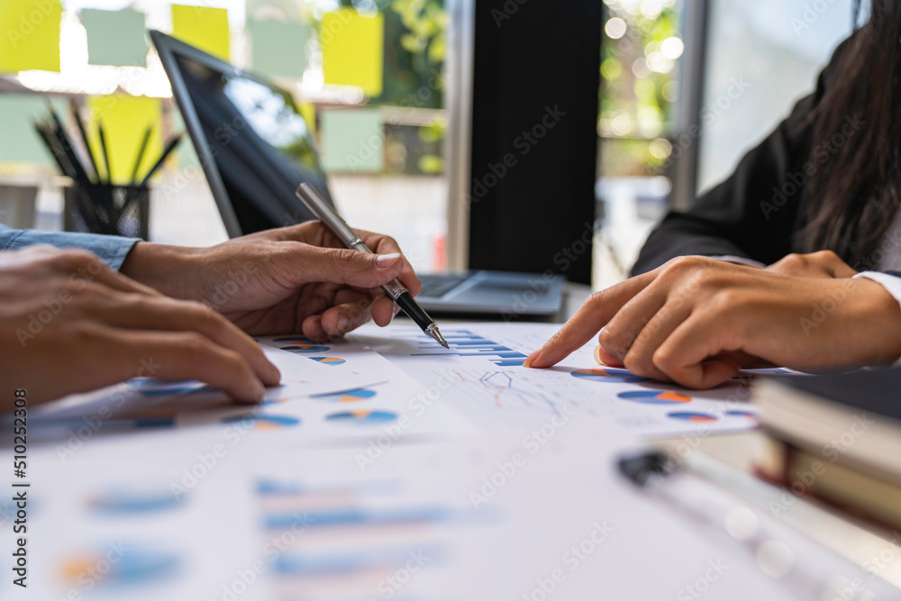 Two business people sit down to analyze financial data from earnings graphs showing the company's earnings to be presented at a meeting.
