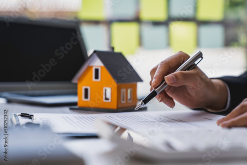 Real estate agent working sign agreement document contract for home loan insurance approving purchases for client with house model and key on table