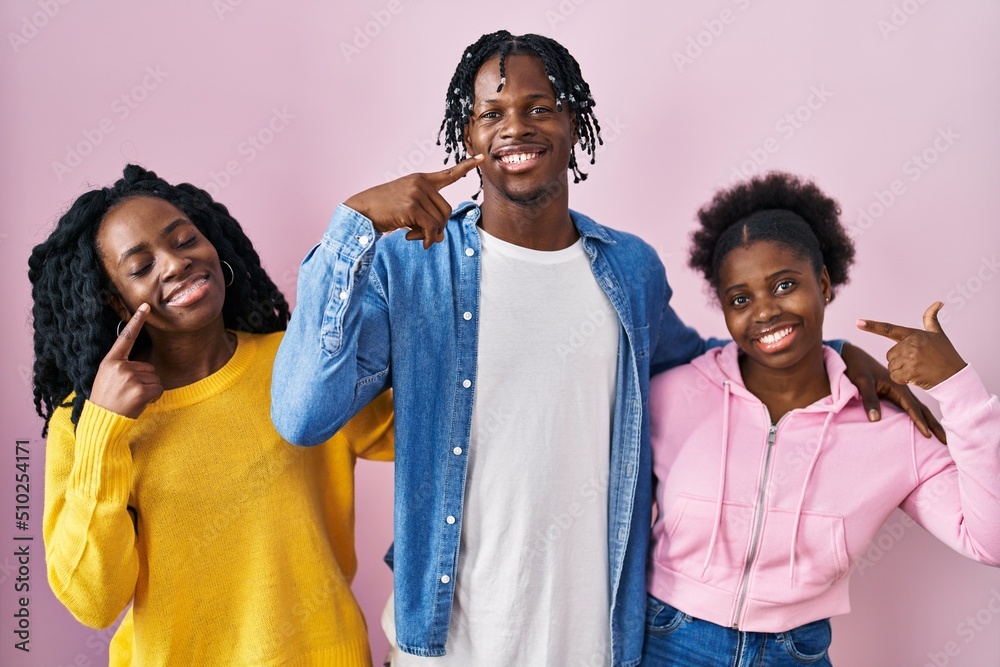 Group of three young black people standing together over pink ...