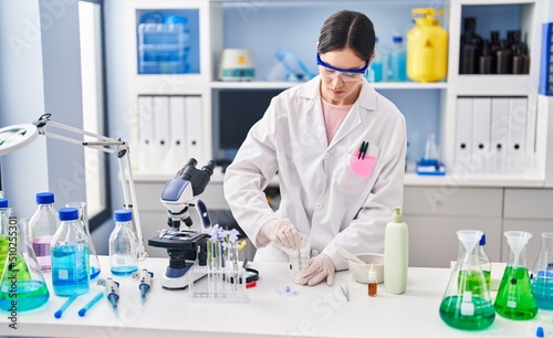 Young woman wearing scientist uniform working at laboratory