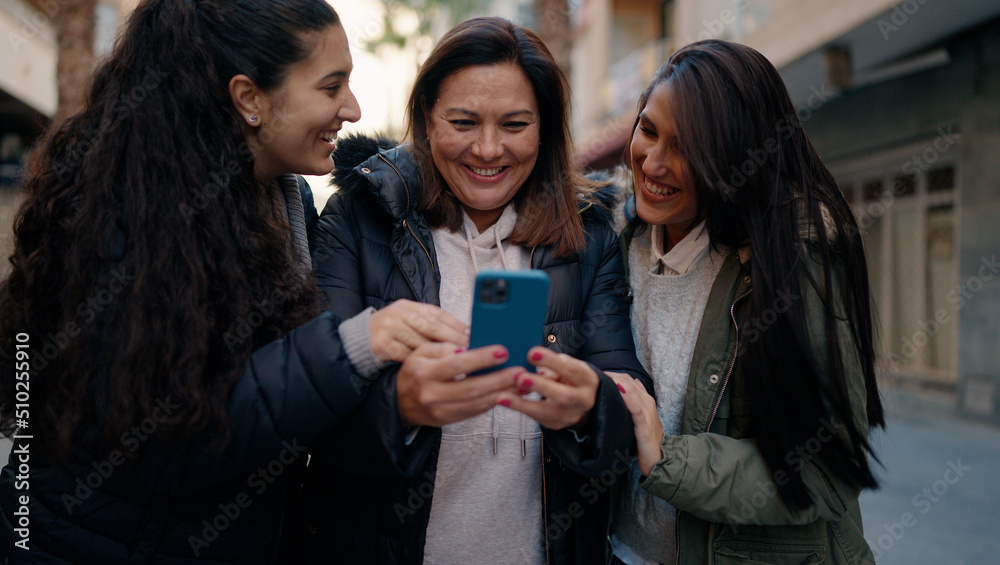 Mother and daugthers using smartphone standing together at street Mother and daugthers using smartphone standing together at street