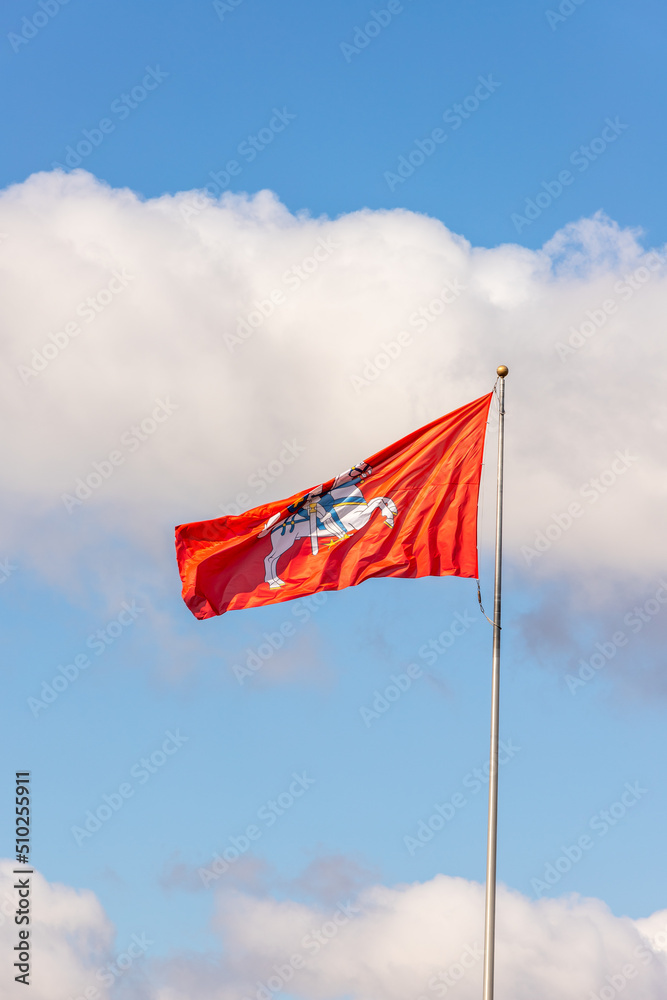 Vertical photo of historical Lithuanian red flag with Vytautas the great figure against sky background. flag with an armour-clad knight on horseback holding a sword and shield. Vertical photo of historical Lithuanian red flag with Vytautas the great figure against sky background. flag with an armour-clad knight on horseback holding a sword and shield.