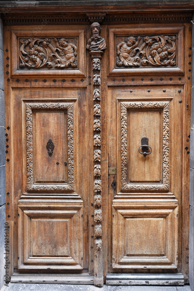 old ornate wooden door with beautiful carvings in Clermont- Ferrand, France.