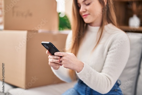 Young blonde woman smiling confident using smartphone at new home