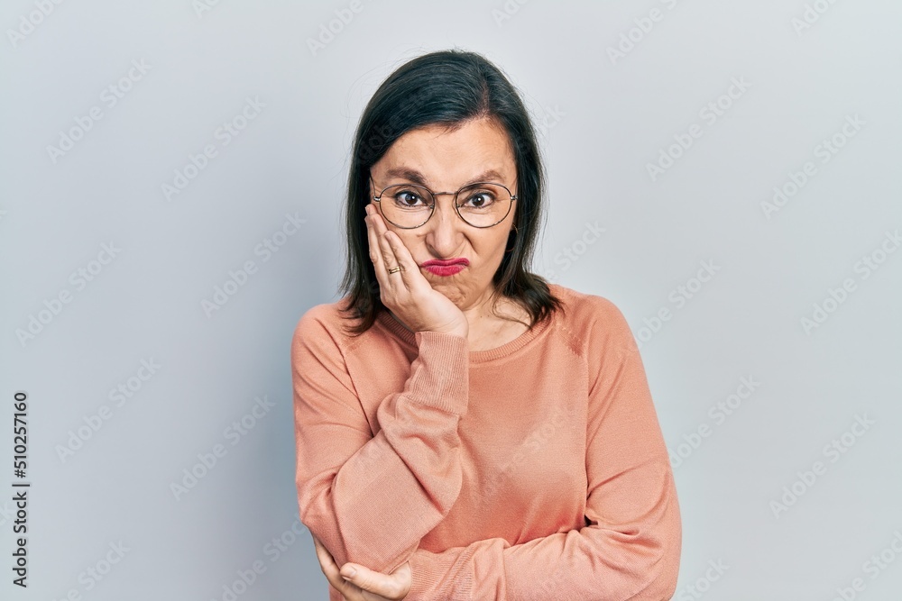 Middle age hispanic woman wearing casual clothes and glasses thinking looking tired and bored with depression problems with crossed arms.