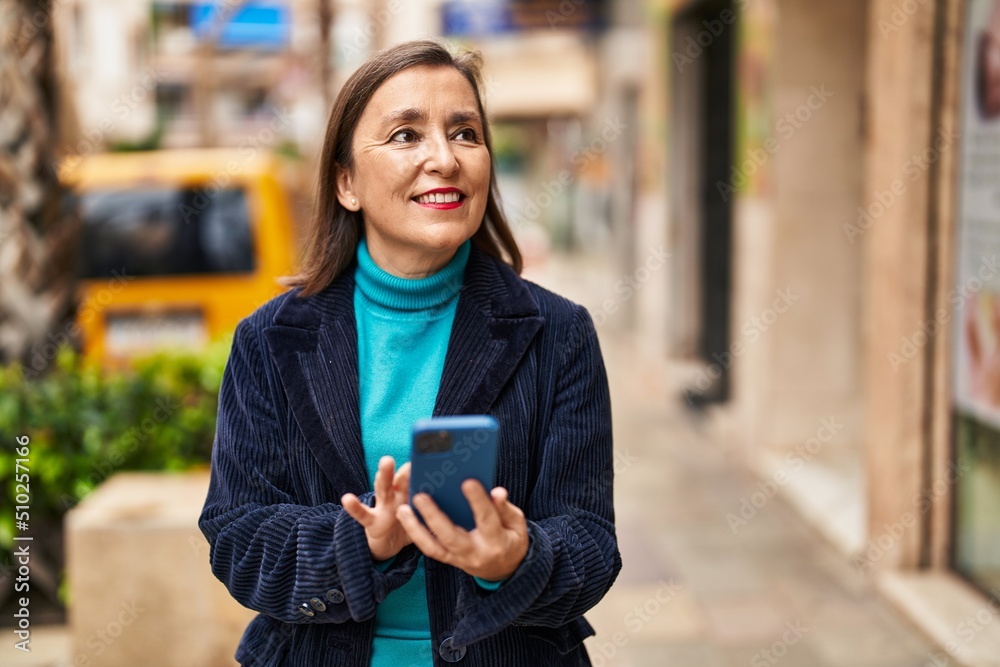 Middle age woman business executive using smartphone at street