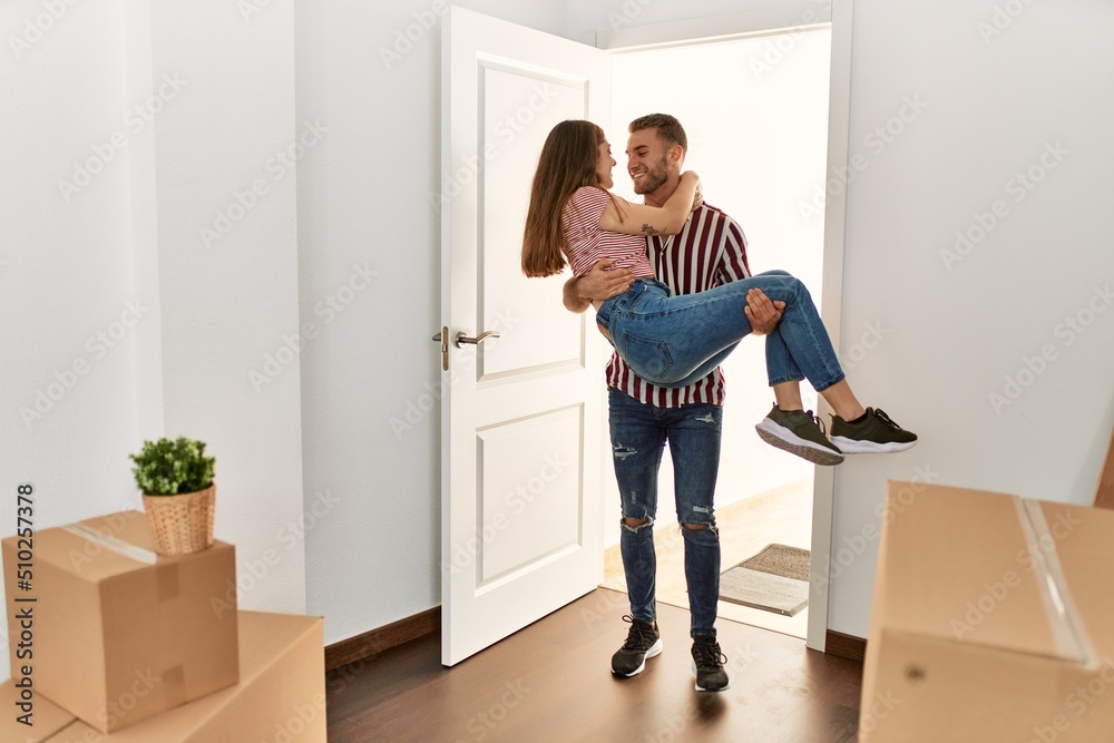 Young caucasian man holding woman in arms gettin in new home door. Young caucasian man holding woman in arms gettin in new home door.