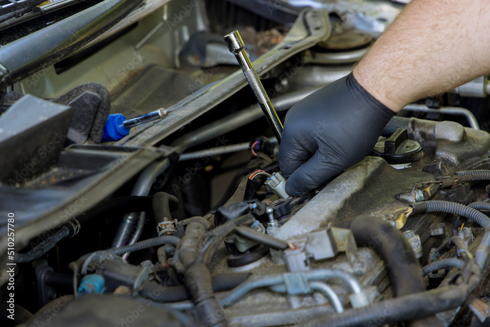 Mechanic carries out diagnostics and replacement of a car spark plug in the engine Mechanic carries out diagnostics and replacement of a car spark plug in the engine