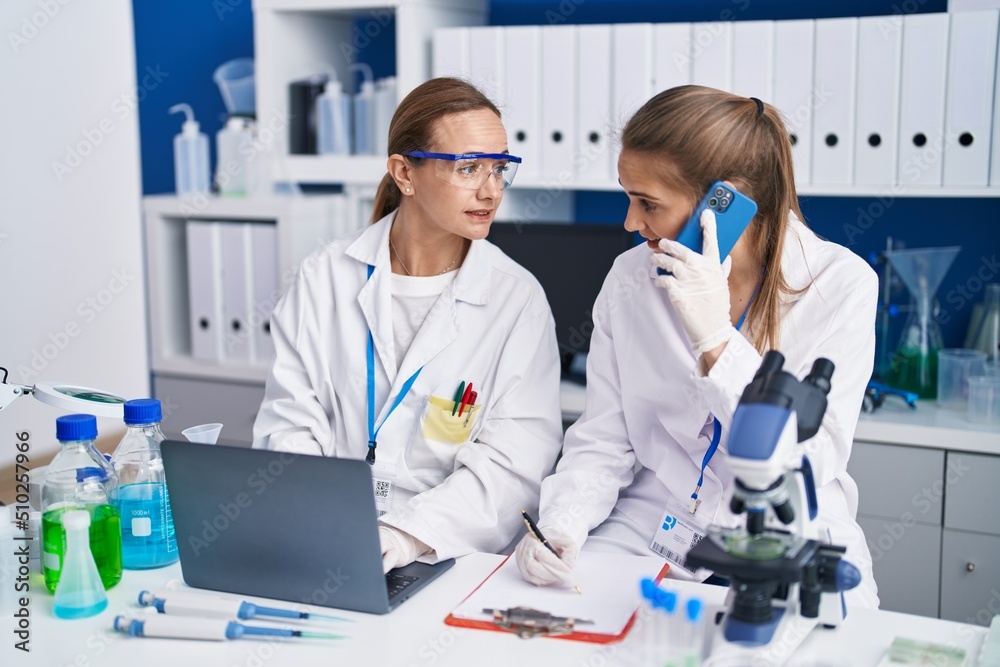 Two women scientists talking on the smartphone working at laboratory Two women scientists talking on the smartphone working at laboratory