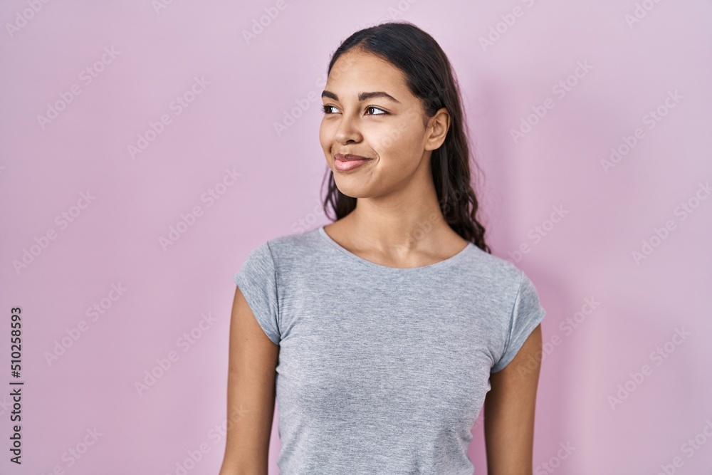 Young brazilian woman wearing casual t shirt over pink background smiling looking to the side and staring away thinking. Young brazilian woman wearing casual t shirt over pink background smiling looking to the side and staring away thinking.