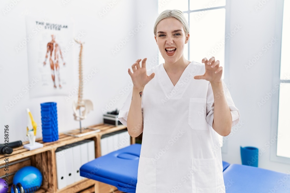 Young caucasian woman working at pain recovery clinic smiling funny doing claw gesture as cat, aggressive and sexy expression Young caucasian woman working at pain recovery clinic smiling funny doing claw gesture as cat, aggressive and sexy expression