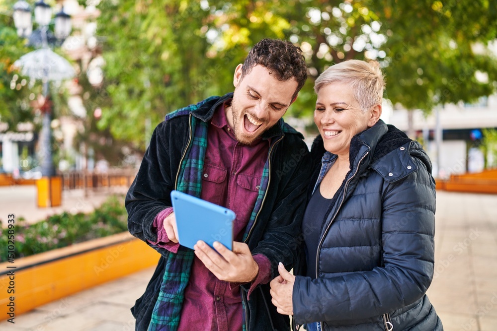 Naklejka premium Mother and son smiling confident using touchpad at park