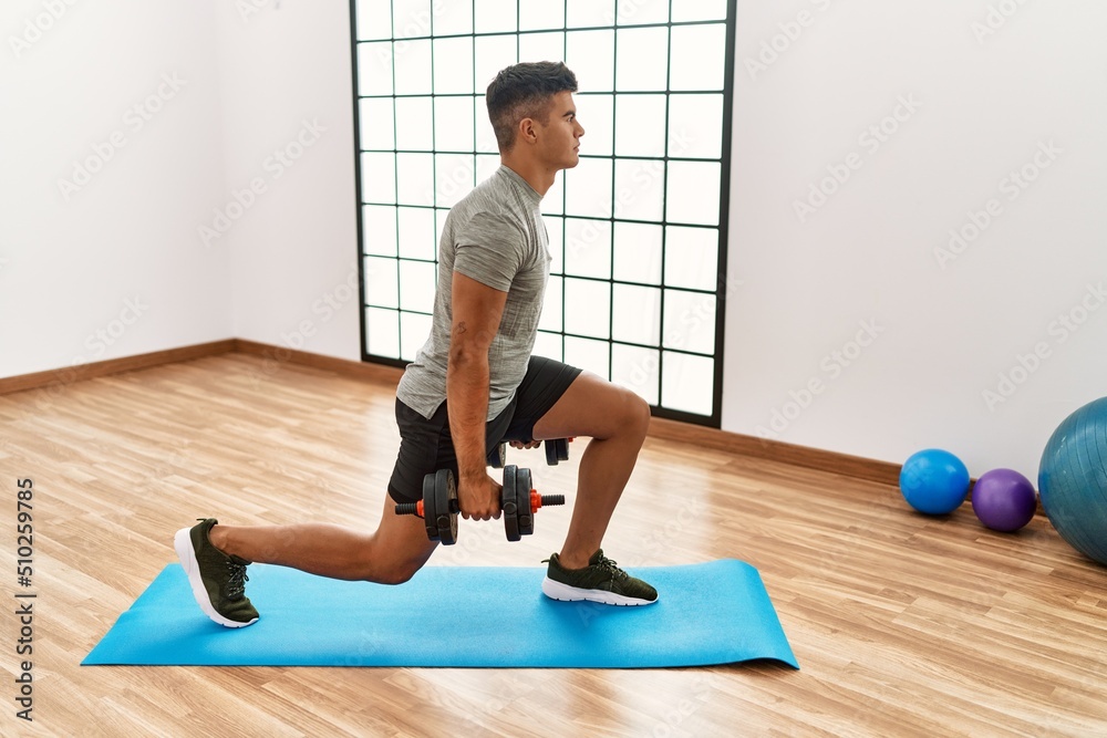 Young hispanic man training using dumbbells at sport center Young hispanic man training using dumbbells at sport center