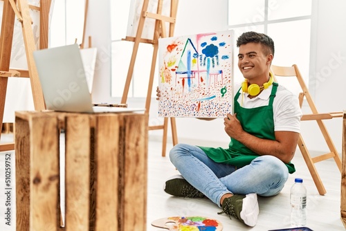Young hispanic man smiling confident having online draw class at art studio