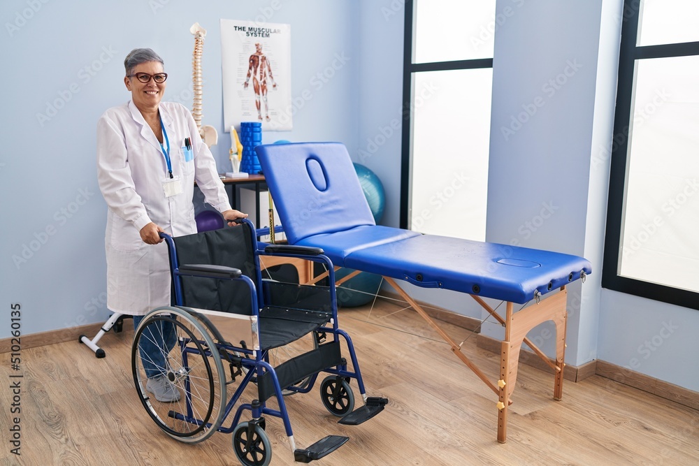Middle age woman with wheelchair looking positive and happy standing and smiling with a confident smile showing teeth Middle age woman with wheelchair looking positive and happy standing and smiling with a confident smile showing teeth