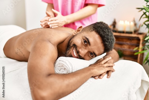 Young african american smiling happy reciving back massage at beauty center.