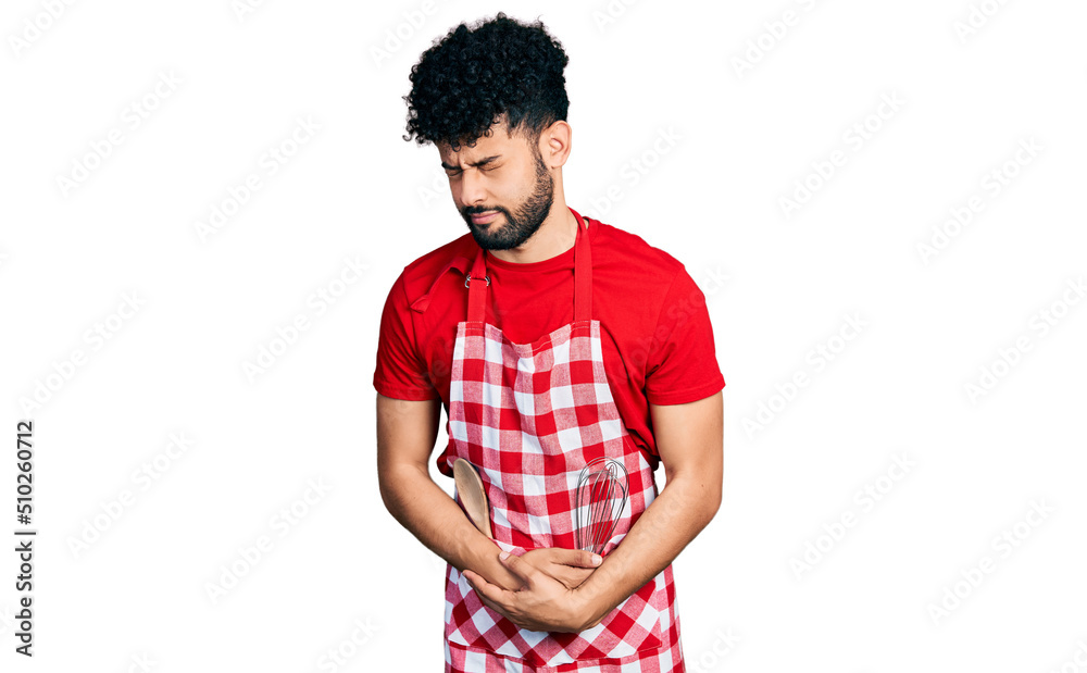 Young arab man with beard wearing cook apron with hand on stomach because indigestion, painful illness feeling unwell. ache concept. Young arab man with beard wearing cook apron with hand on stomach because indigestion, painful illness feeling unwell. ache concept.