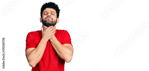 Young arab man with beard wearing casual red t shirt shouting and suffocate because painful strangle. health problem. asphyxiate and suicide concept.