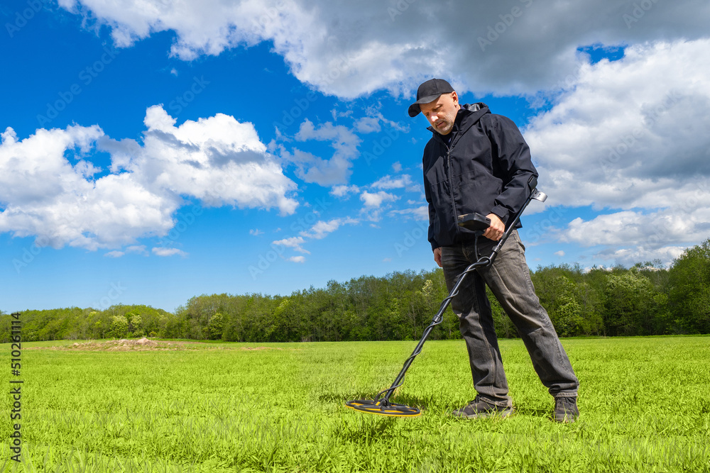 Archaeologist with metal detector. Man archaeologist stands at edge of forest. Equipment for archaeological searches. Archaeologist looking for metal underground. Electro magnetic metal detector use Archaeologist with metal detector. Man archaeologist stands at edge of forest. Equipment for archaeological searches. Archaeologist looking for metal underground. Electro magnetic metal detector use