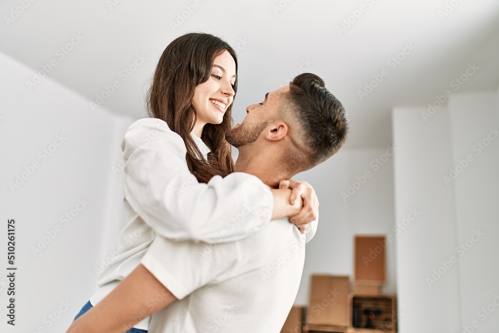 Young hispanic man holding woman in arms and hugging at new home. Young hispanic man holding woman in arms and hugging at new home.