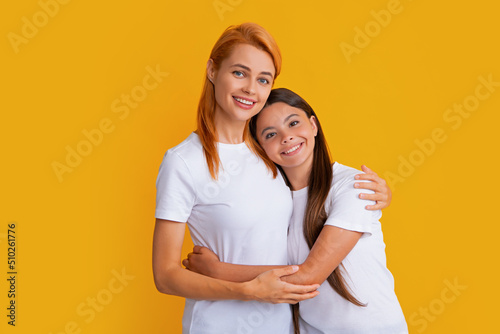 Mom mum and kid daughter in t-shirt embrace cudding isolated on yellow color background studio. Mothers day love family.