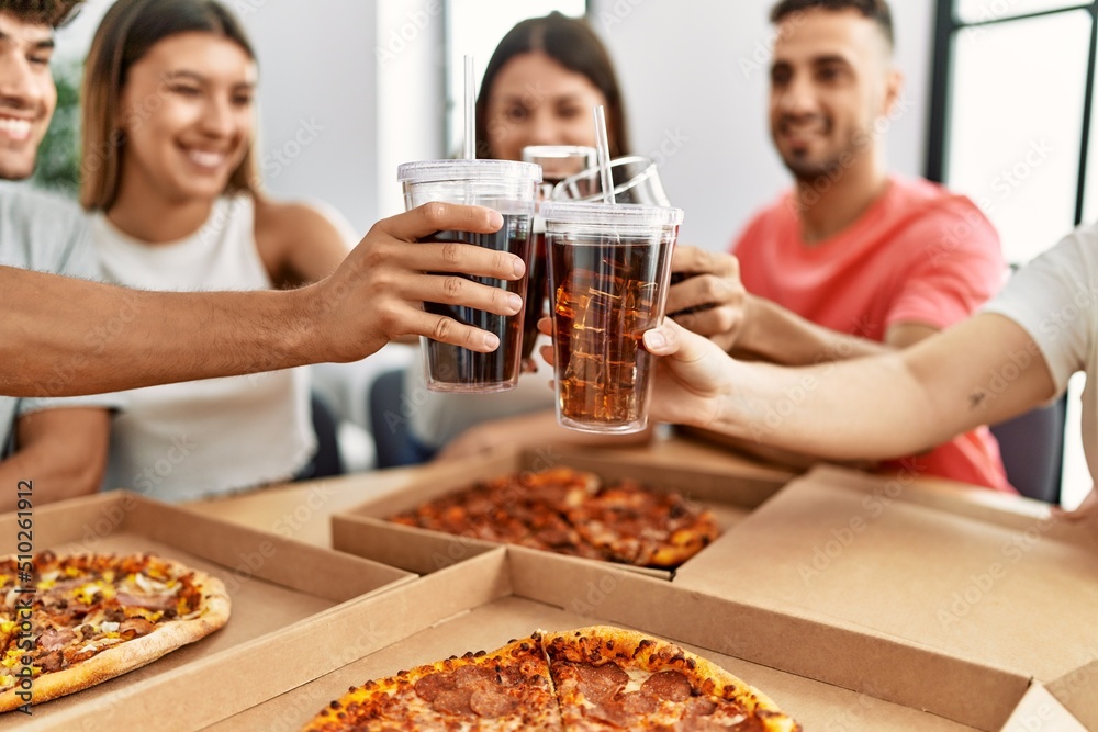 Group of young friends smiling happy eating italian pizza and toasting with cola beverage at home. Group of young friends smiling happy eating italian pizza and toasting with cola beverage at home.
