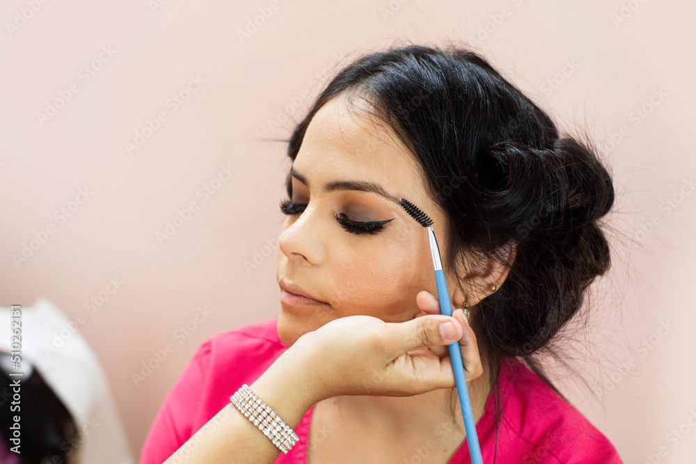 Makeup artist applying eyelashes to a Hispanic woman Makeup artist applying eyelashes to a Hispanic woman