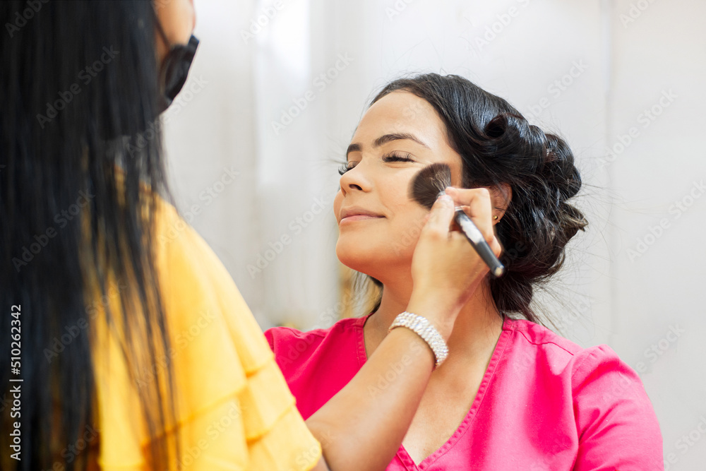 Fototapeta premium Makeup artist using brushes dusting cheeks.